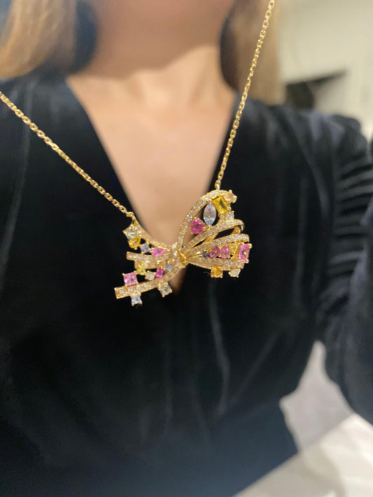 Gold butterfly pendant necklace with pink, yellow & clear gemstones, worn on black top