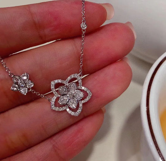 Elegant diamond flower necklace with sparkling petals, held gently in hand for close-up view.