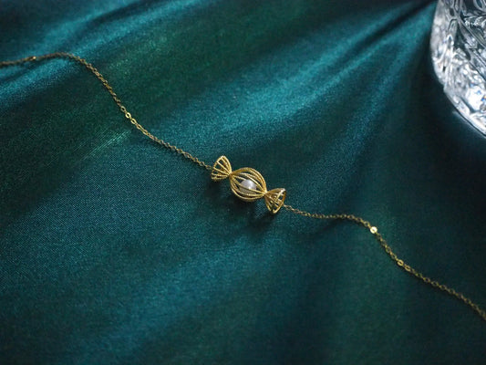 Gold candy-shaped pendant necklace with pearl on teal velvet, elegant Sydney jewellery