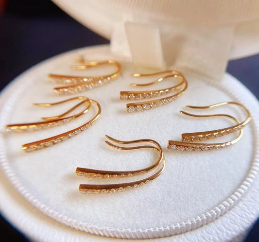 Elegant gold hoop earrings with sparkling crystals, displayed in a white velvet jewelry box