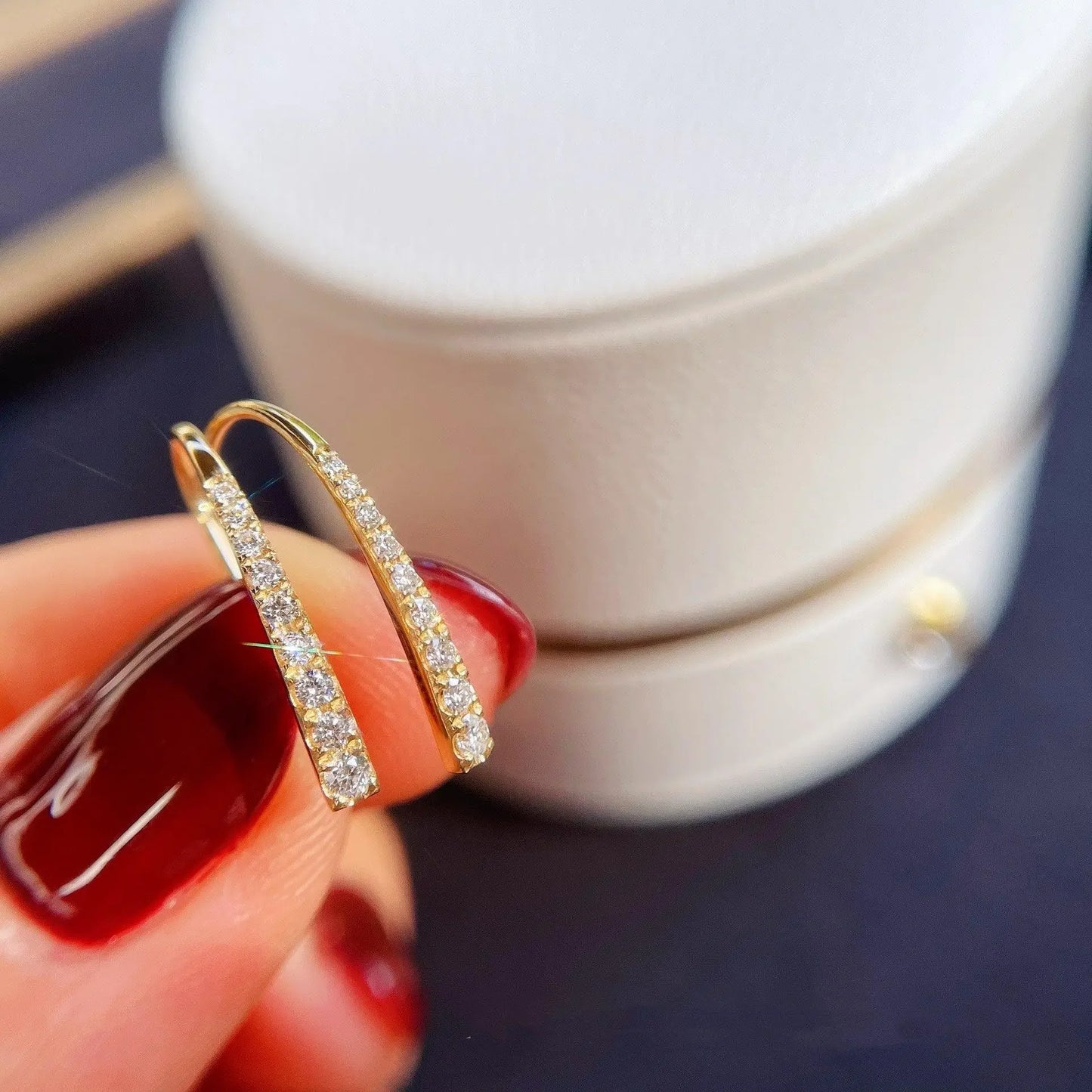Gold hoop earrings with sparkling diamonds, held against a white jewelry box, perfect for Sydney fine jewellery lovers.