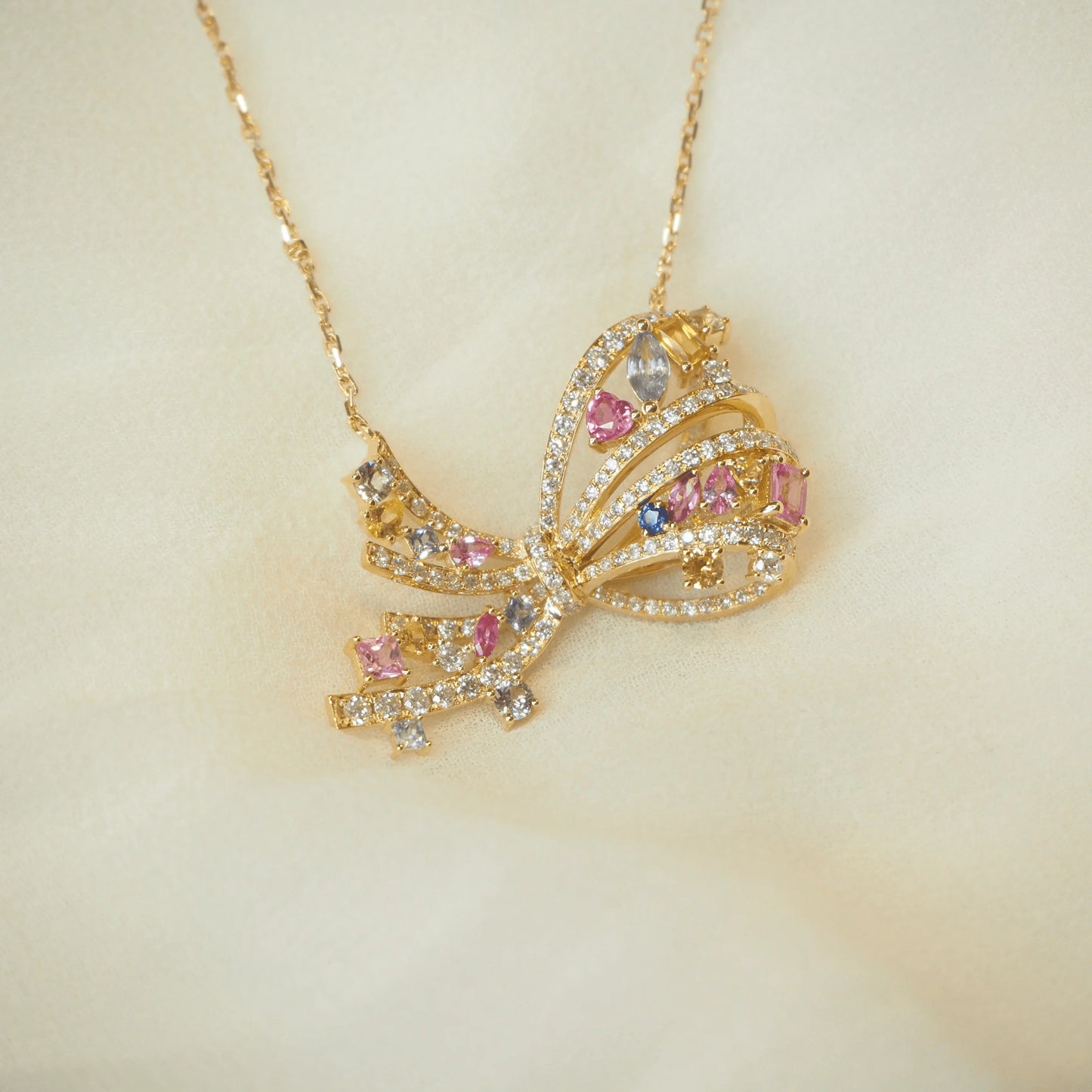 Gold butterfly pendant necklace with pink, blue, and clear gemstones on a delicate chain