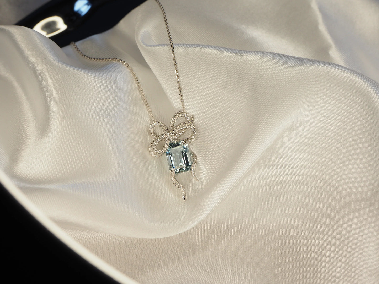 Elegant bow pendant necklace with aquamarine gemstone and diamond accents on silk, Sydney jewellery